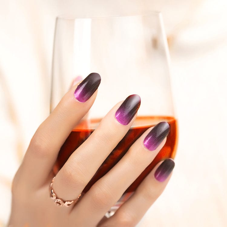 Hand holding mug with purple to black gradient nail wraps ombré manicure