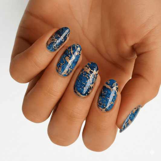 Blue lapis lazuli nail wraps with gold veining on hand showing marble stone effect