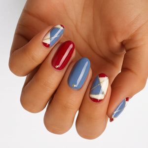 Nail wraps in red and blue with cream geometric panels and gold line accents