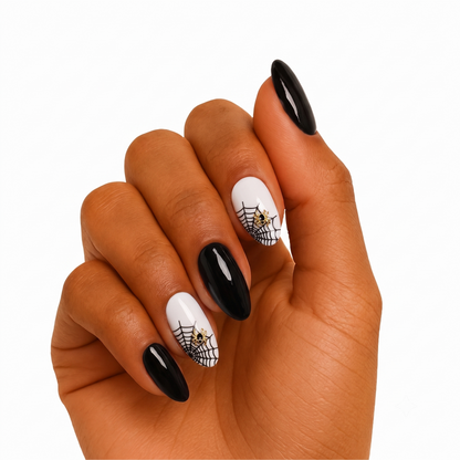 Glossy black and white press-on nails with spiderweb design and gold spider charms