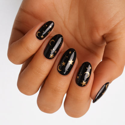 Glossy black nail wraps with gold moon and star celestial design, almond shape