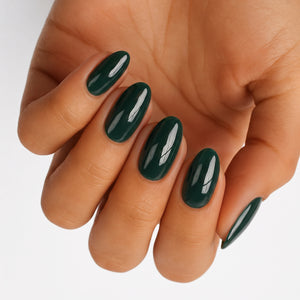Glossy dark green nail wraps on an oval manicure, solid high-shine finish.