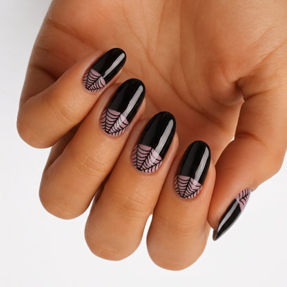 Glossy black nail wraps with sheer pink spiderweb design near cuticle, oval shape