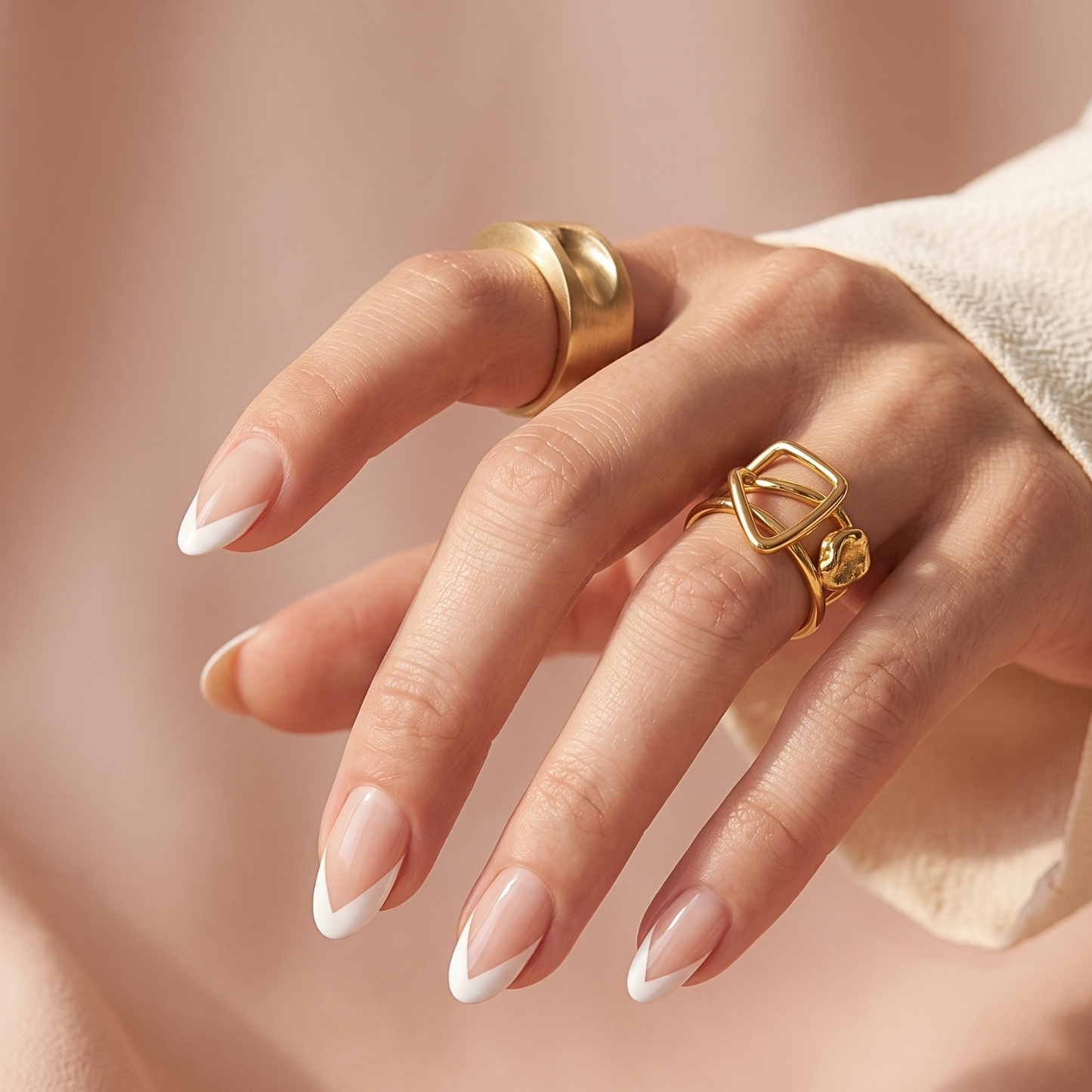 Sheer nude nail wraps with a white V-tip French manicure on almond-shaped nails.