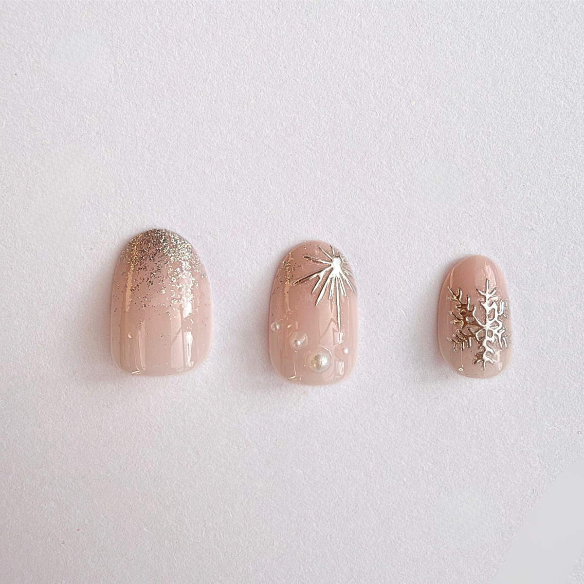 Nude soft gel press-on nails with glitter tips, silver snowflakes and pearl accents