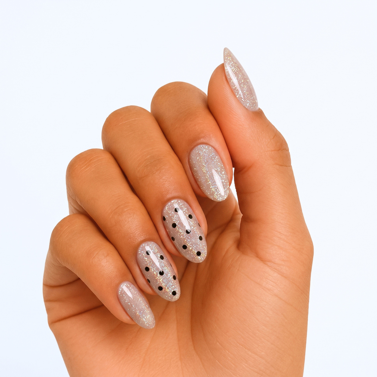 Sheer glittery nude press-on nails with scattered black polka dot accents