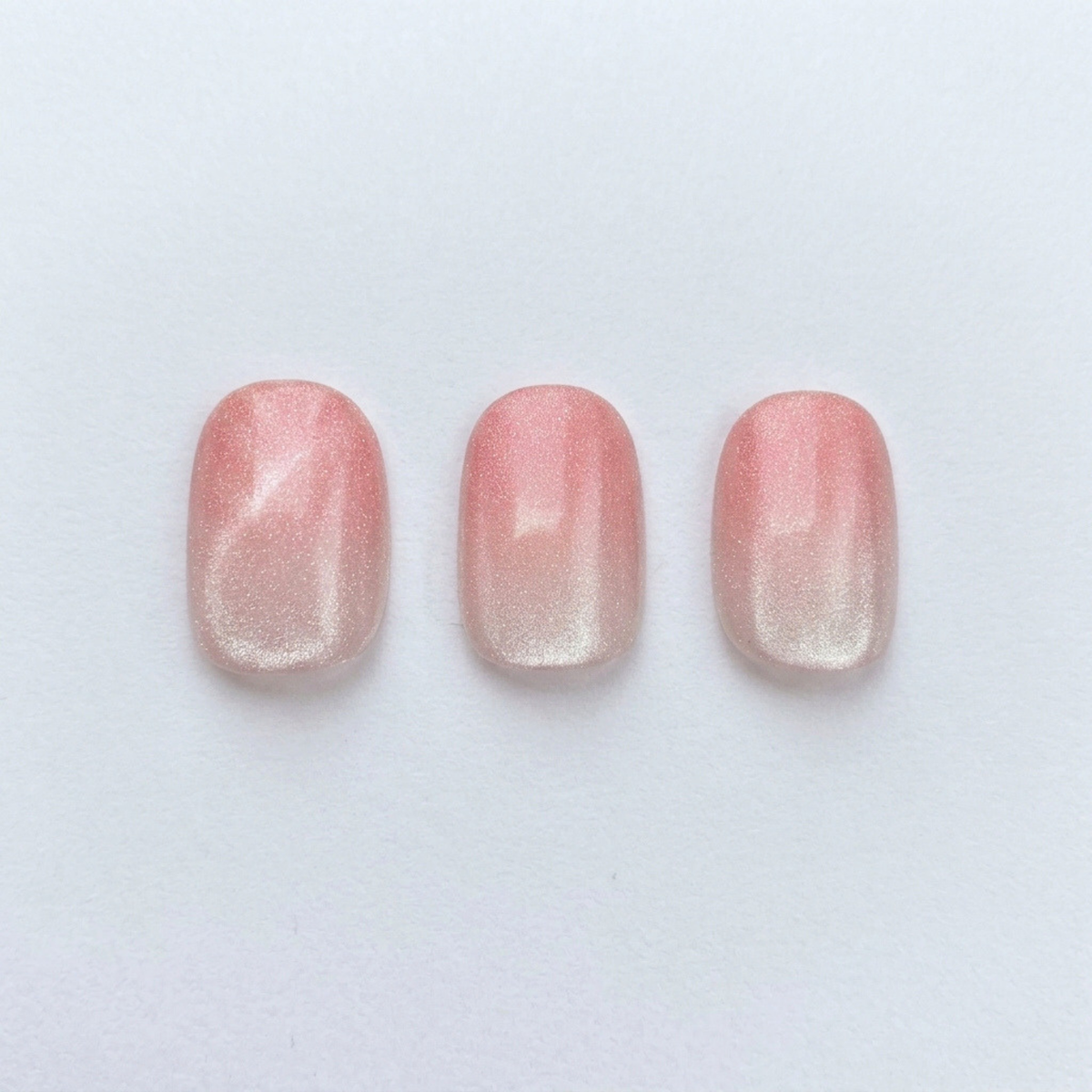Pink shimmer press-on nails with sheer ombre fade, glossy finish