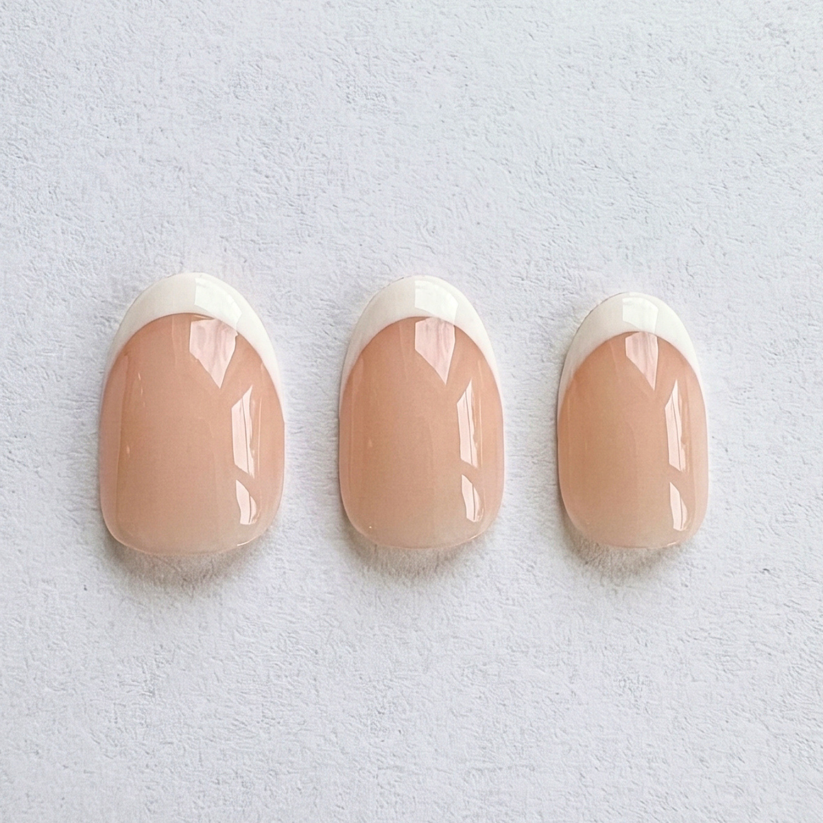 Nude pink press-on nails with glossy white French tips, short round shape