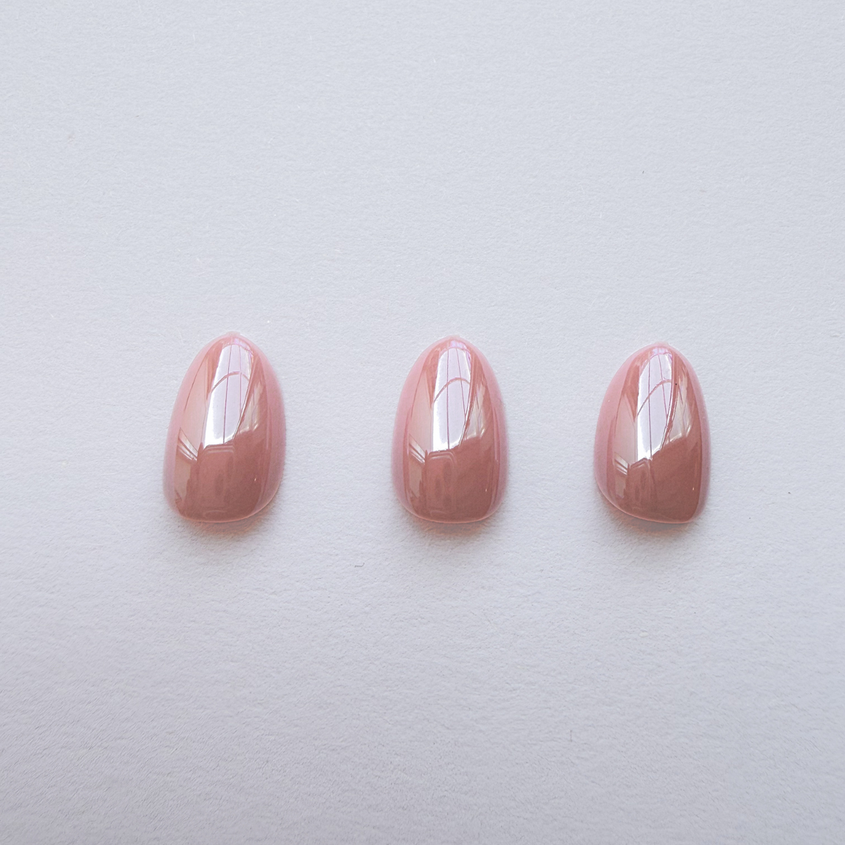 Glossy mauve-pink press-on nails, solid color, almond shape, three nail set