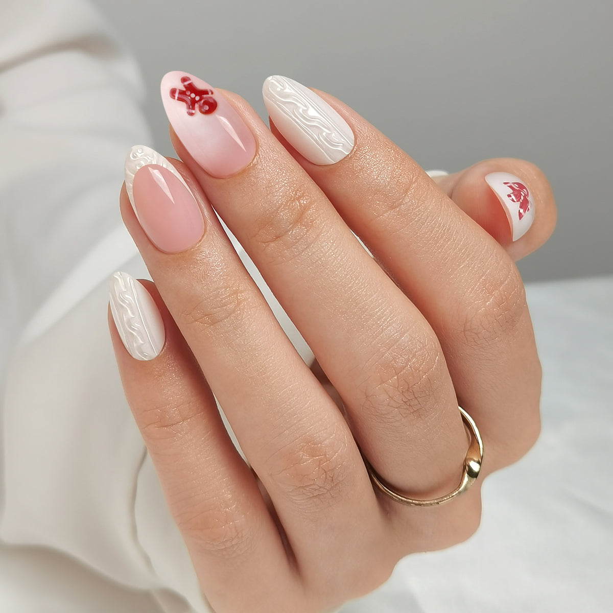 Glossy nude-pink press-on nails with white swirl accents and red gingerbread man design