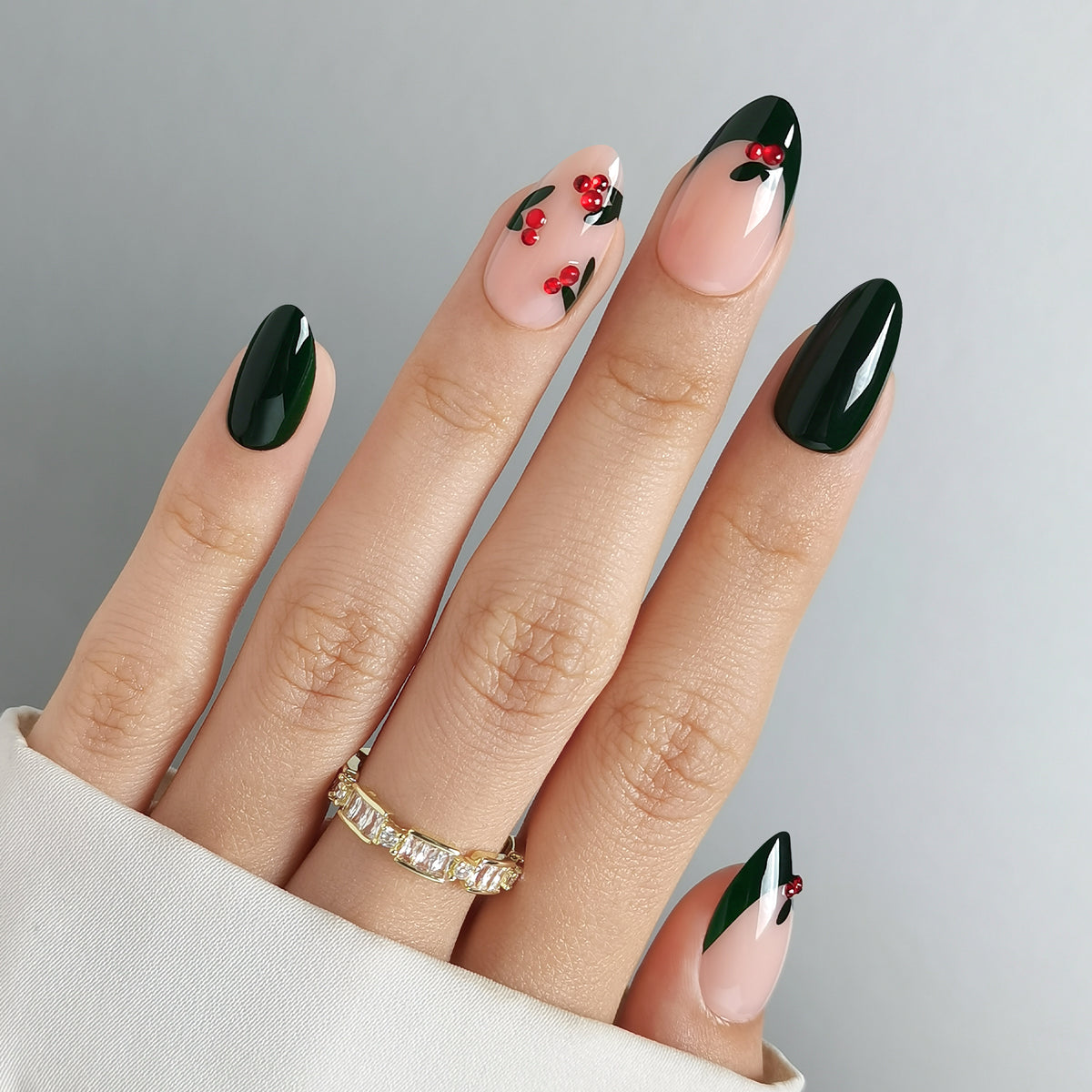 Glossy dark green almond press-on nails with holly berry accents and nude French tips