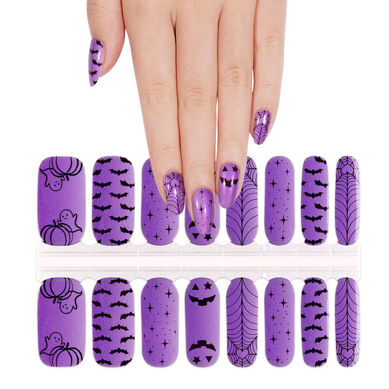 Purple nail wraps with black Halloween prints: bats, spiderwebs, pumpkins, ghosts, jack-o'-lanterns