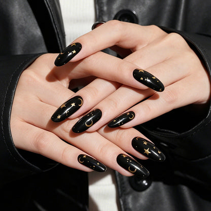 Glossy black almond press-on nails with gold moon and star celestial design