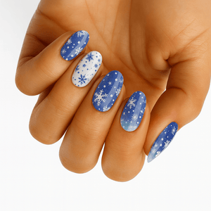 Blue winter nail wraps with white snowflakes on hand showing festive manicure design