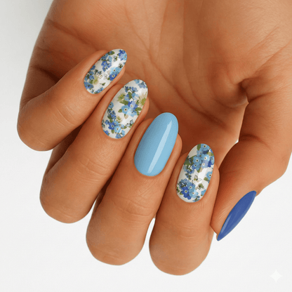 Blue floral nail wraps with daisy pattern on hand showing spring nail art design