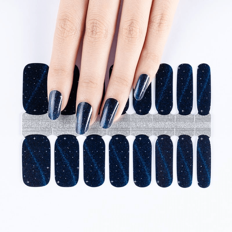 Navy blue glittery nail wraps on hand with celestial sparkle effect