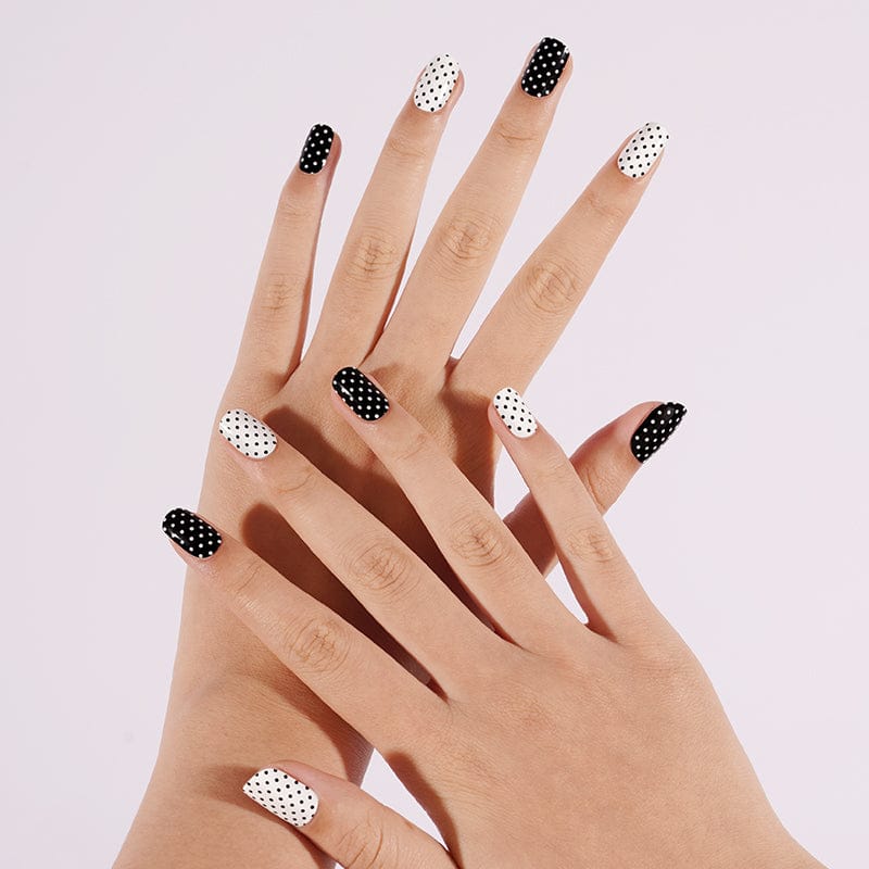 Black and white polka dot gel nail wraps on hands showing alternating dotted pattern