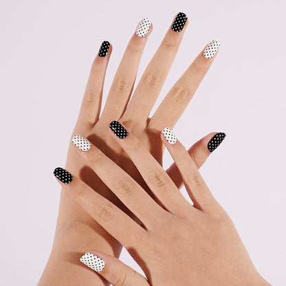 Black and white polka dot gel nail wraps on hands showing alternating dotted pattern
