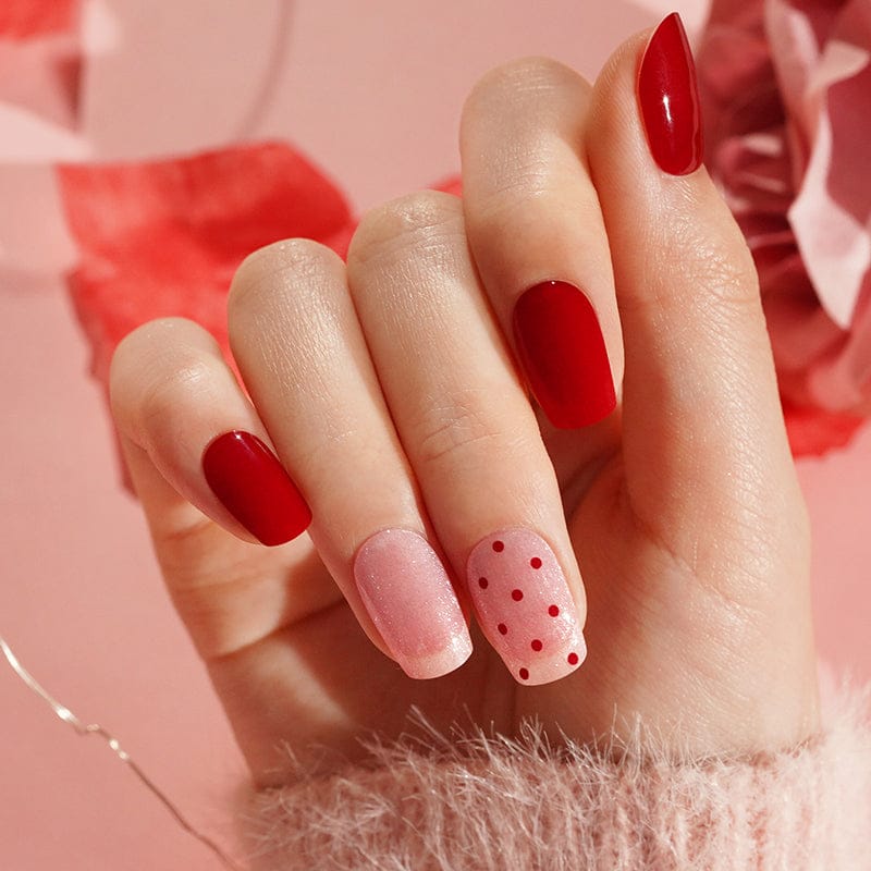 Hand wearing red and pink polka dot gel nail wraps for at-home manicure