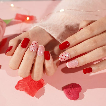 Cherry red and pink dotted gel nails on hands with Valentine's themed manicure design