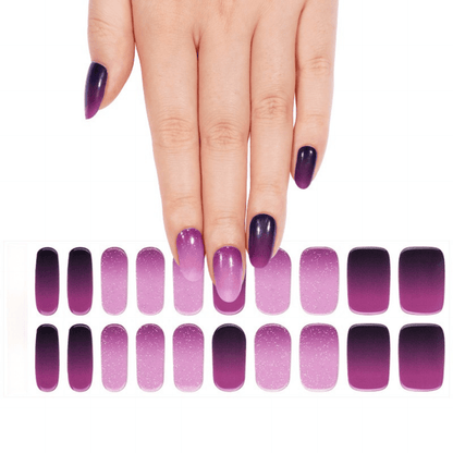Hand with purple gel nails next to ombre nail wrap sheet in plum gradient shades